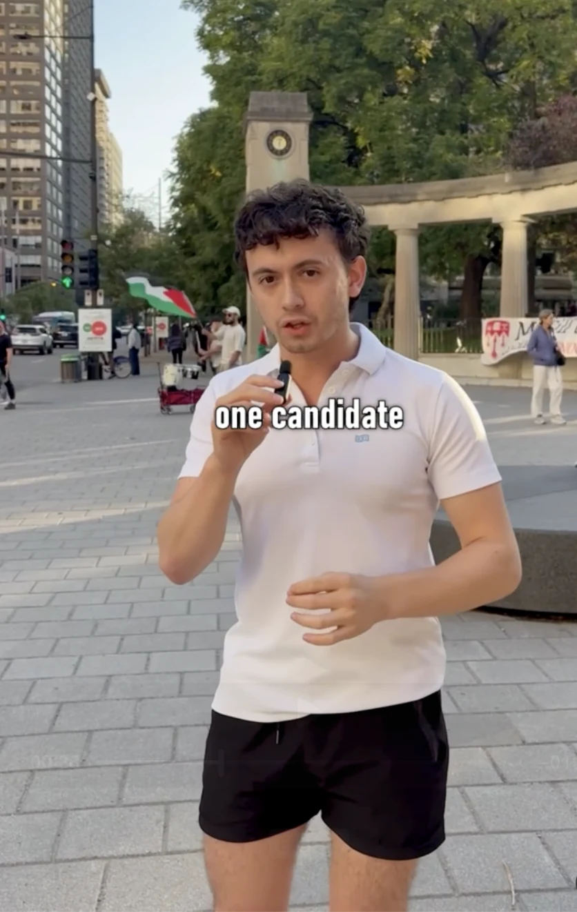 Justice holding a microphone outdoors in a white polo shirt