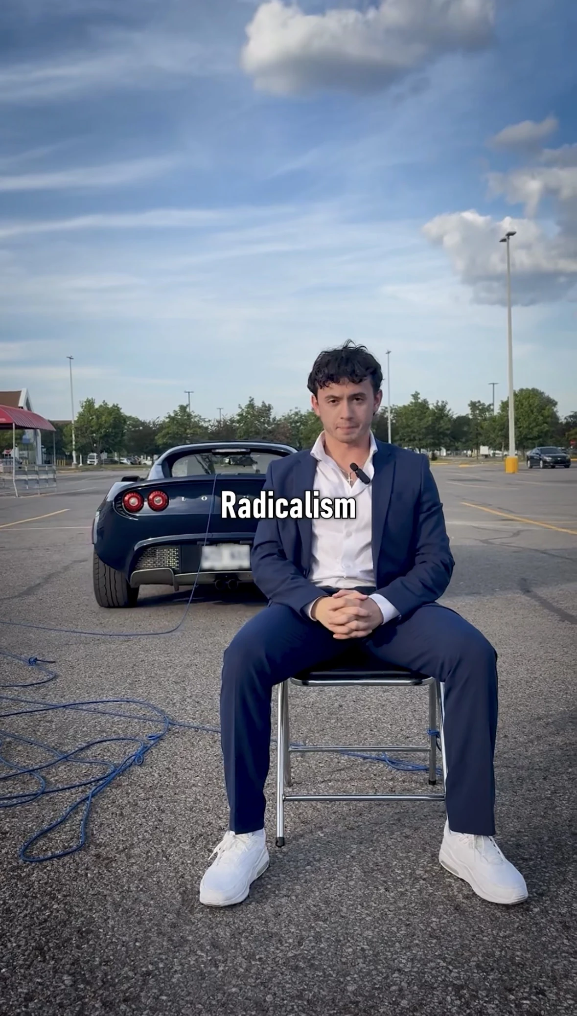 Justice seated in a navy suit in front of a sports car